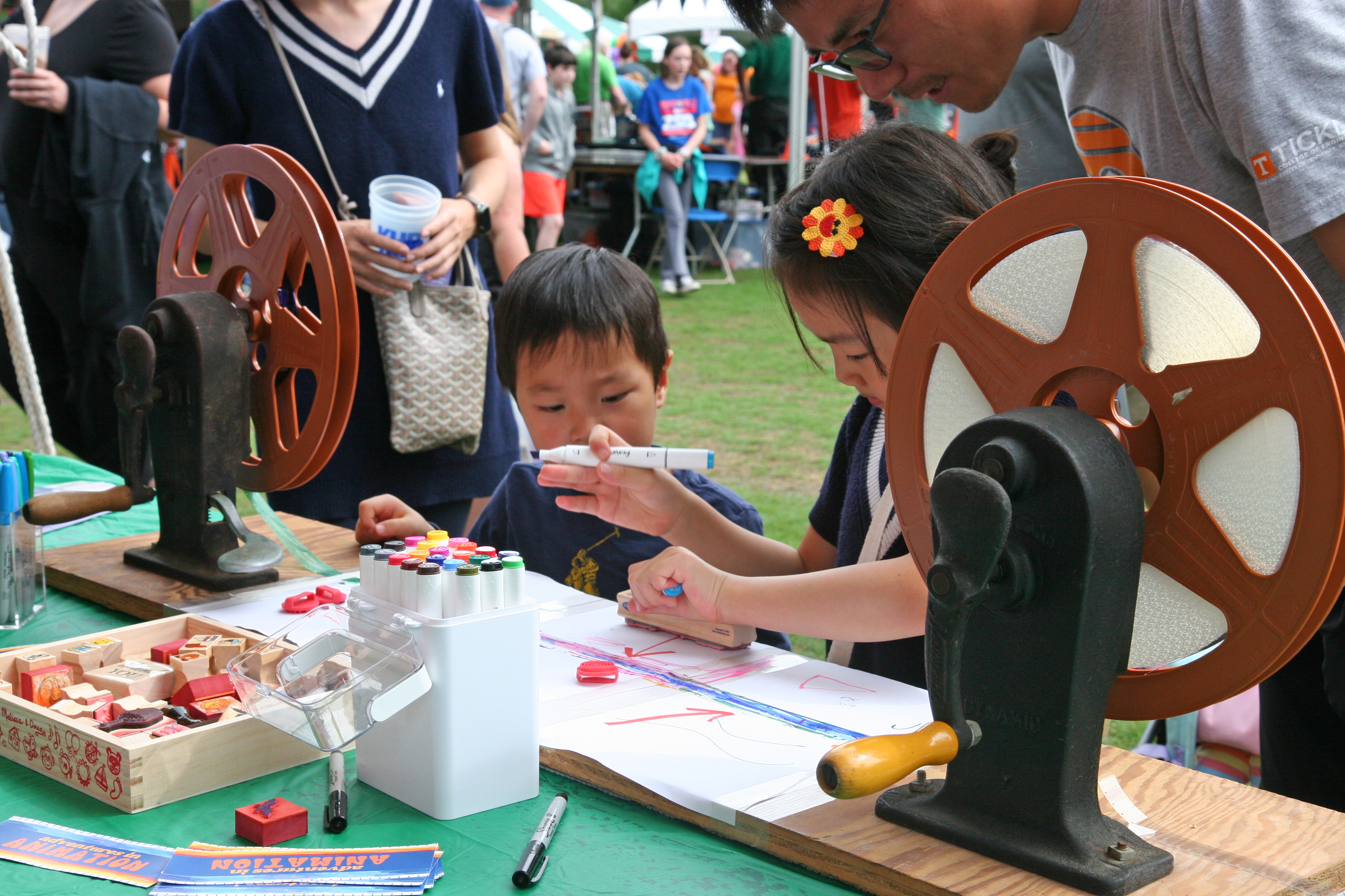 kids stamp a strip of film between two large reels