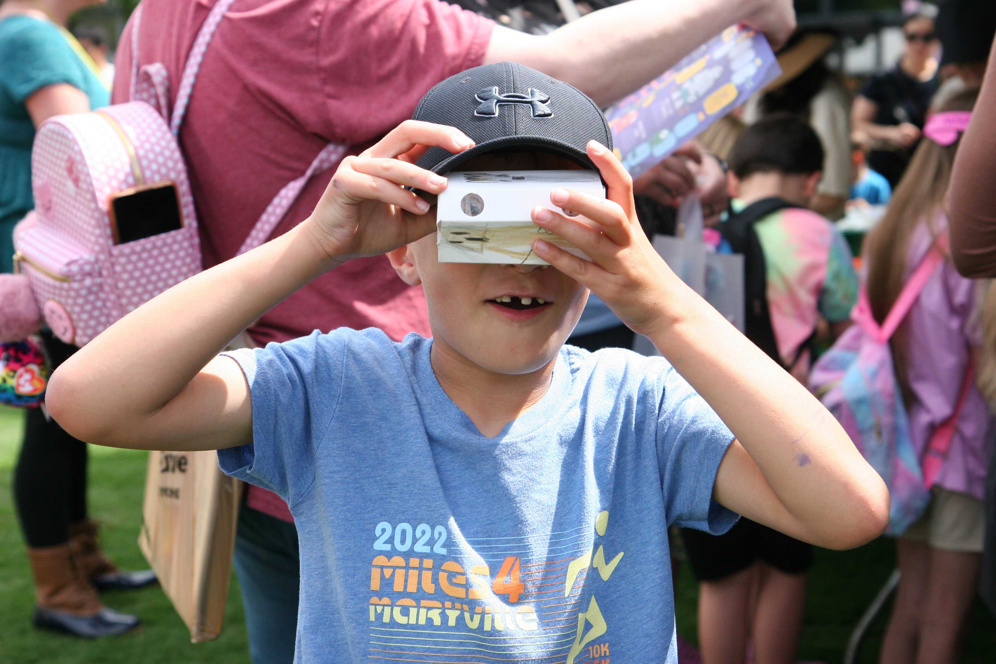 young boy holds up paper craft binoculars