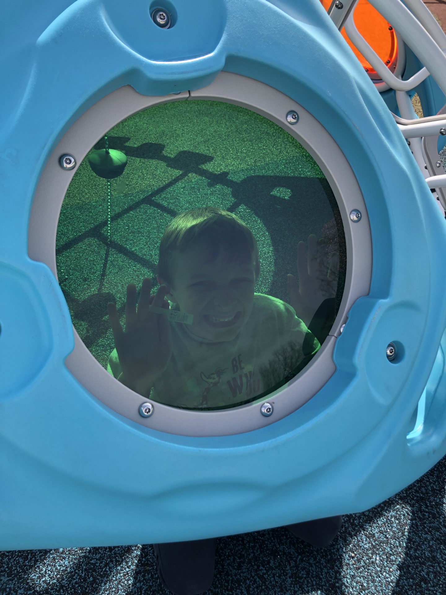 Boy presses face to window of a play structure