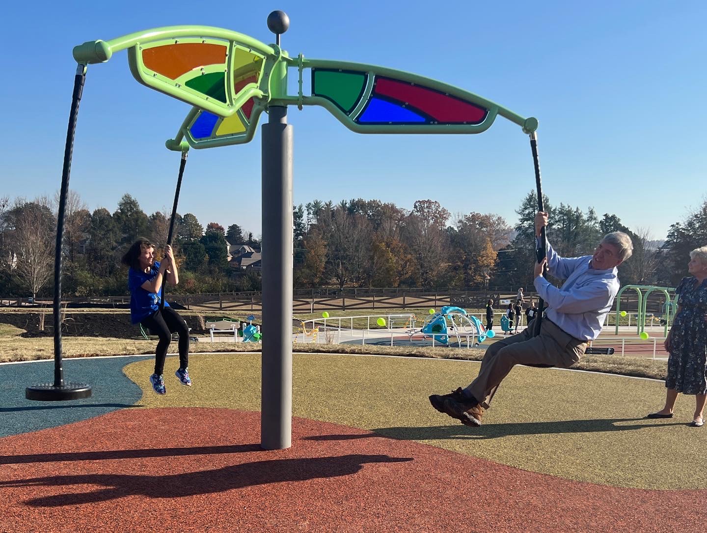 senior man and child swing together on an outdoor play structure