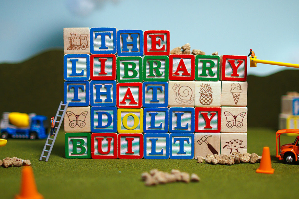 Primary Color wooden blocks spell out THE LIBRARY THAT DOLLY BUILT