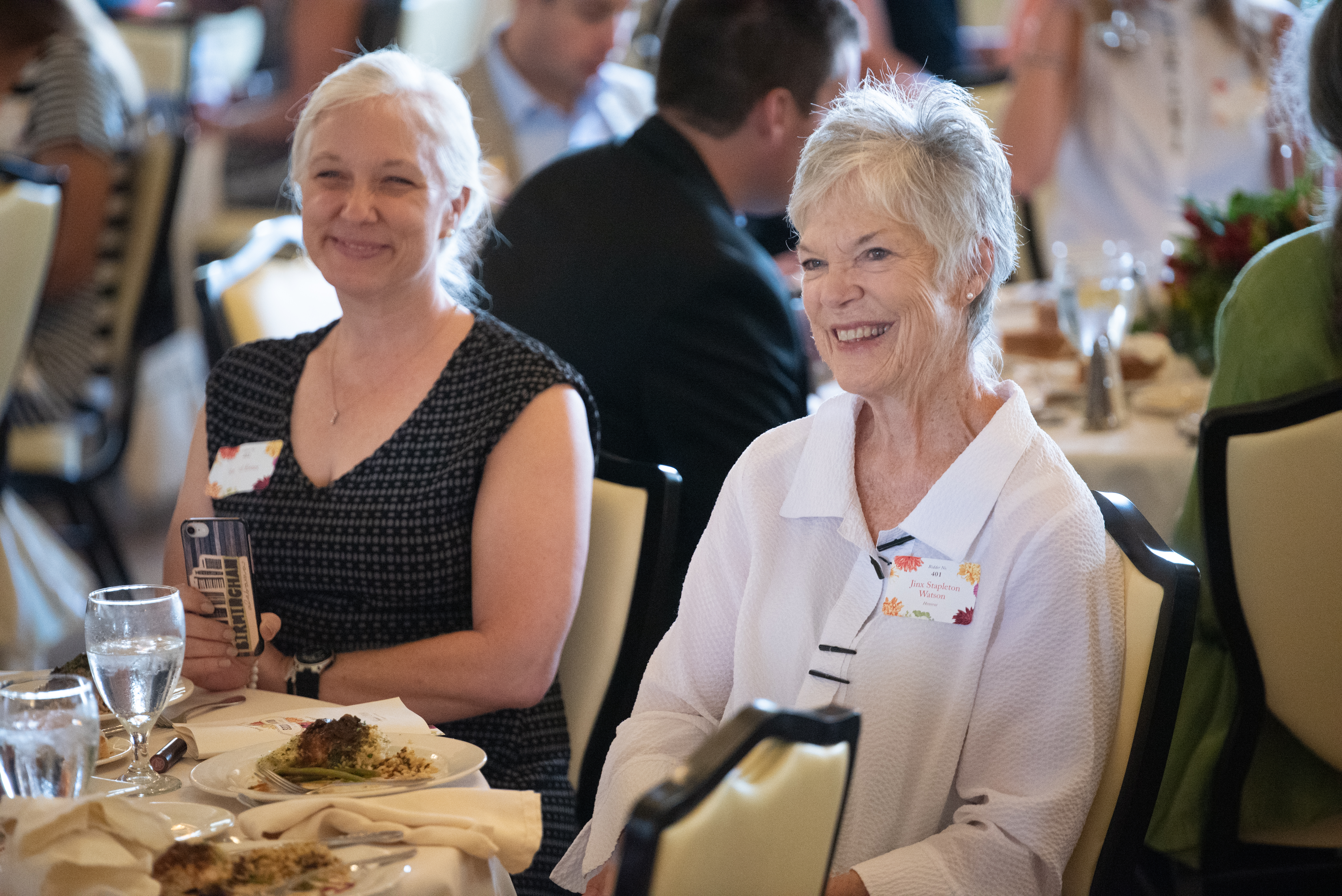 Jinx Watson seated at a table in the ballroom of Cherokee Country Club as the presentation of the Seeds of Literacy award begins