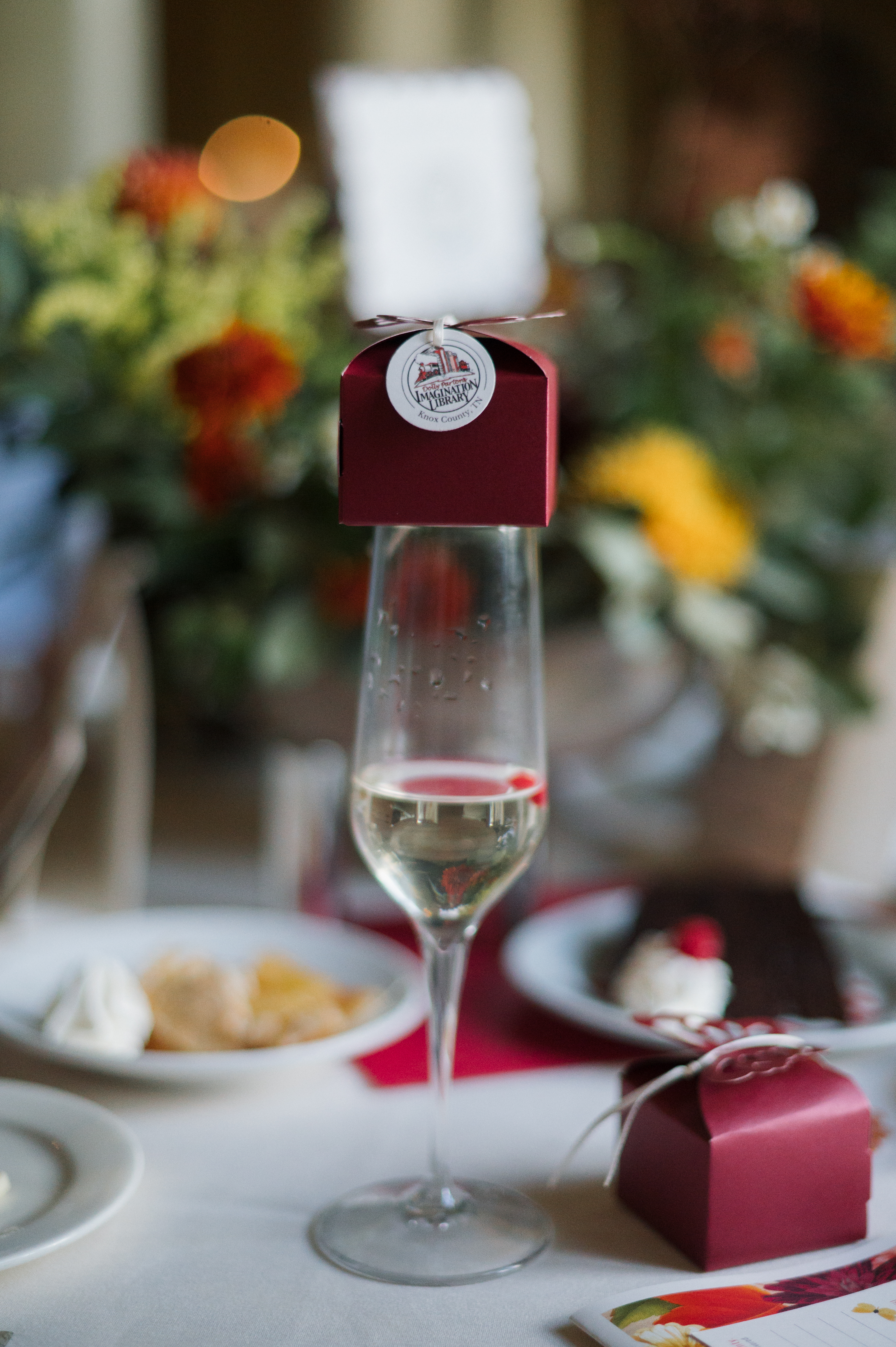 A small red gift box sitting atop a flute of champagne