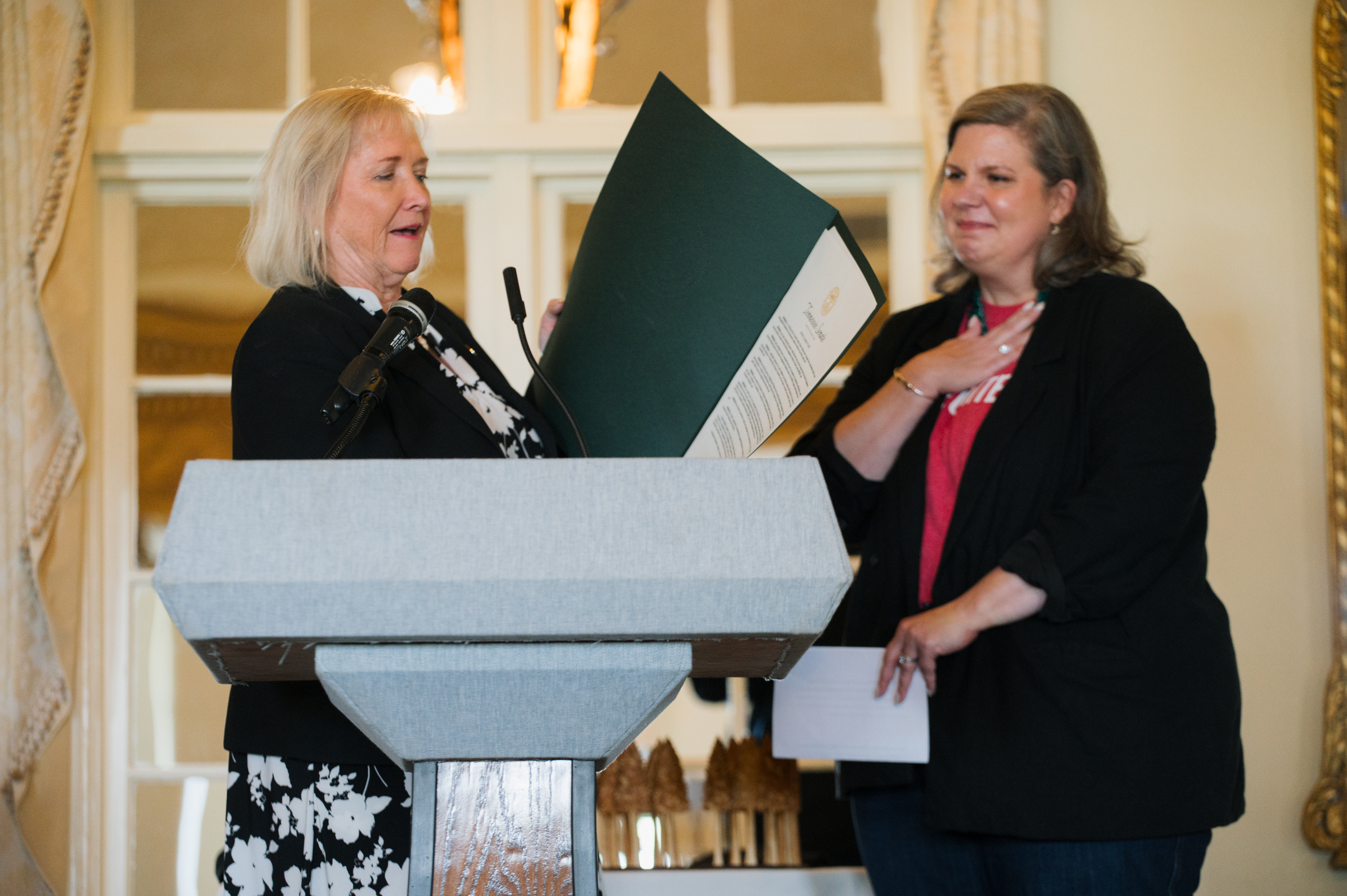 Senator Massey, left, holds a green folder with a letter of recognition from the Senator's Office for Ellie Kittrell, right.