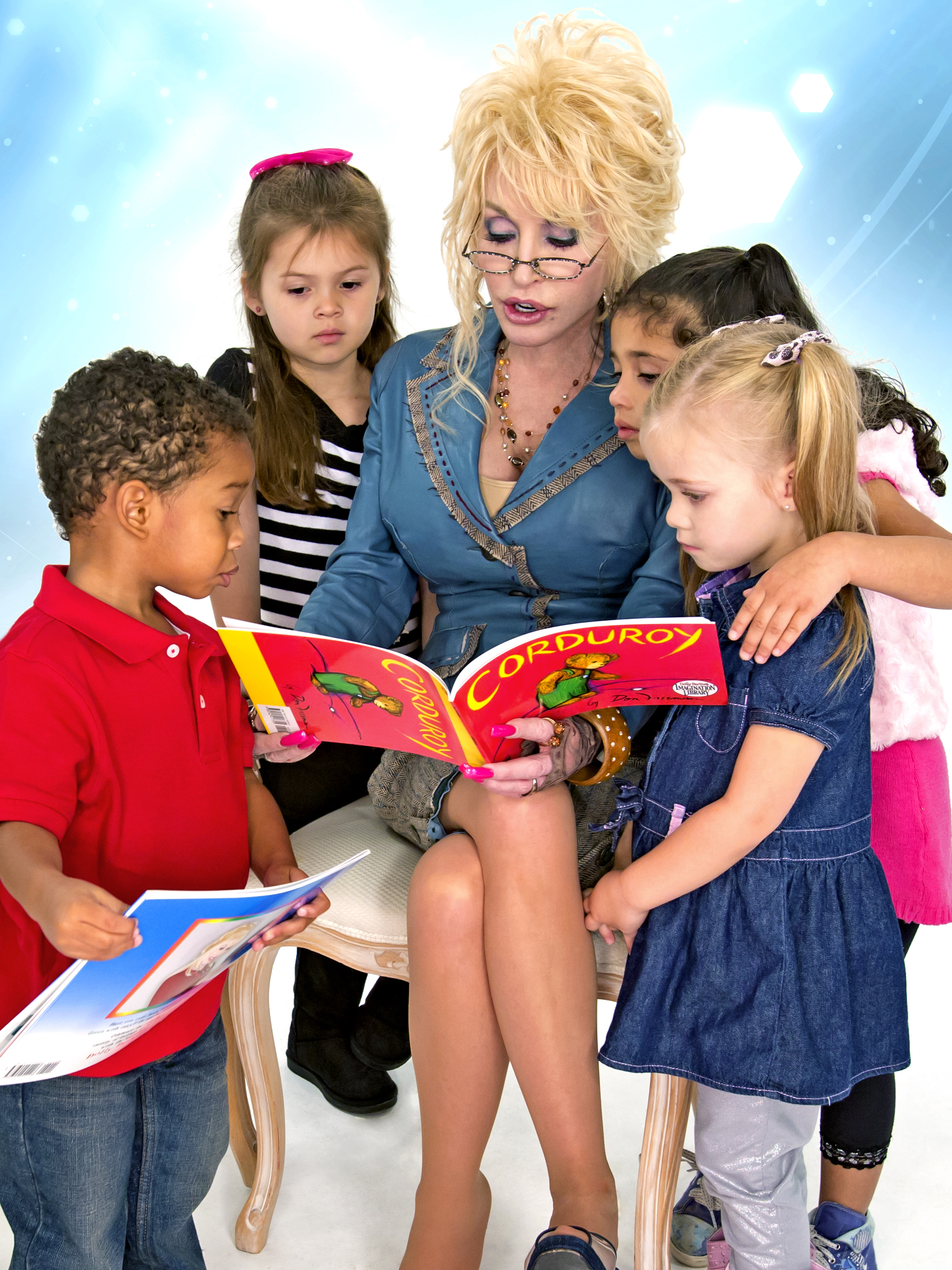 photo of Dolly Parton seated, reading to four young children