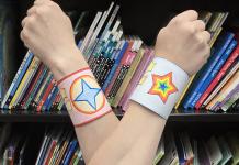 photo of colorful paper bracelets on wrists, arms crossed in an "x"