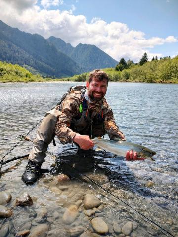 Alex holding a fish in a river