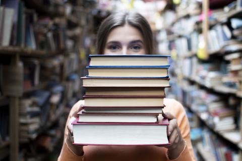 woman holding stack of books