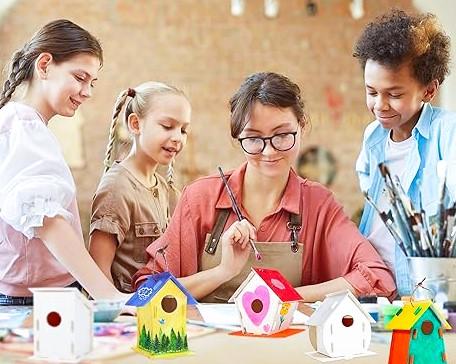 Four people painting birdhouses.