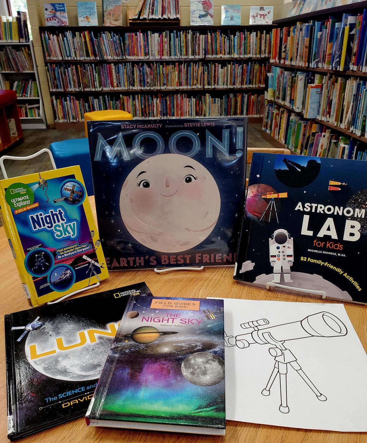 Books about space and a coloring sheet of a telescope on a table in South Knoxville Branch library.