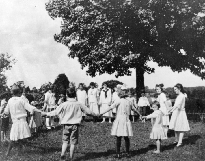 children hold hands and play outside ca.1917