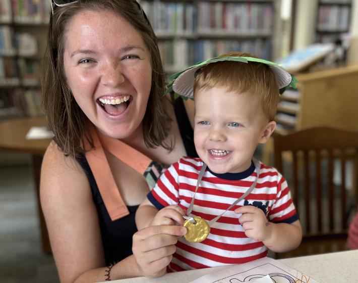 mom and son smiling widely as they show off a completed craft