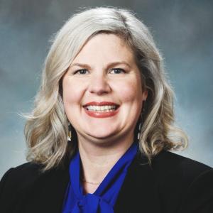 A photo of a smiling woman in a black jacket